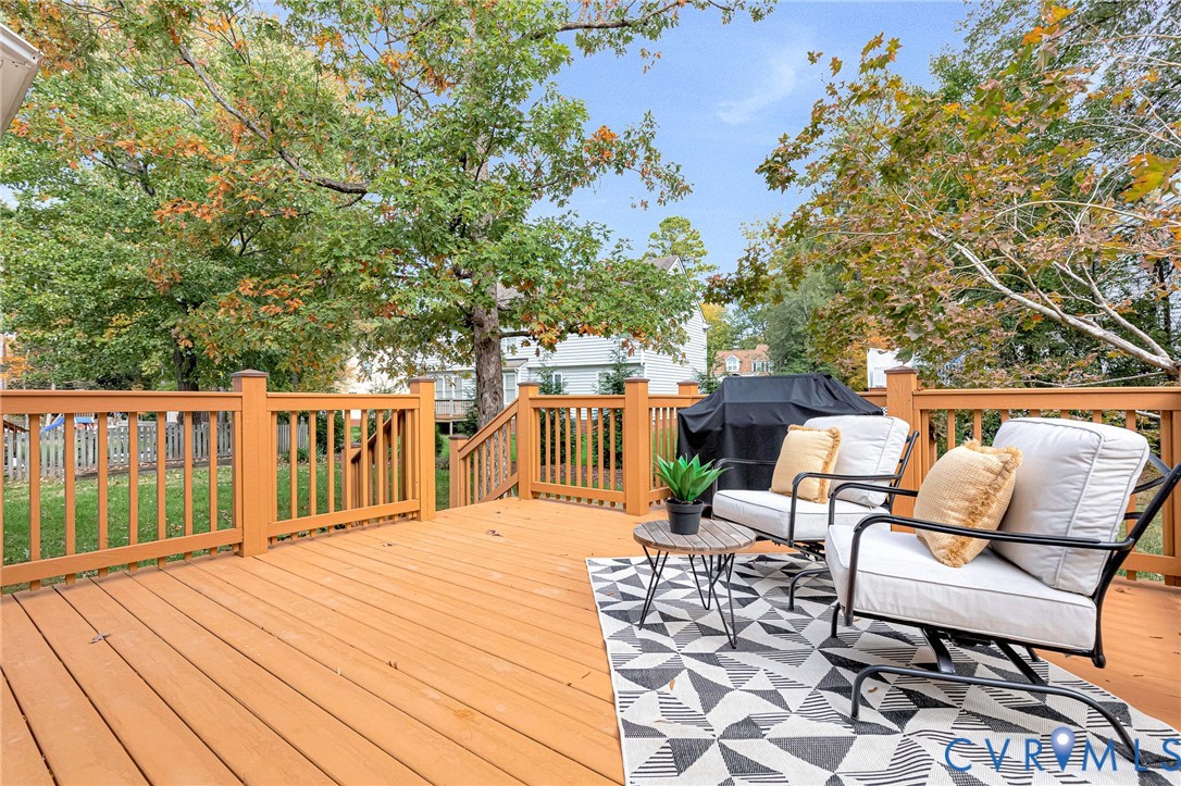 Elevated wood deck featuring vertical baluster railings and stairs leading to a backyard with mature trees
