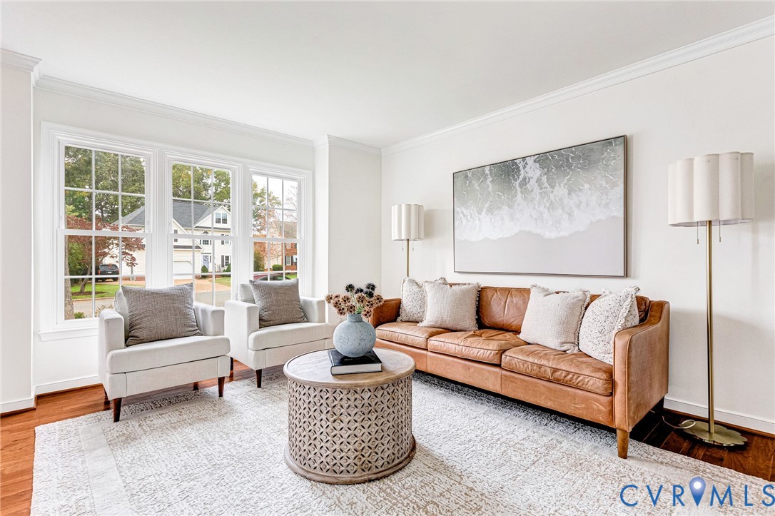 Living area featuring wood-finish flooring, crown molding, and large multi-pane windows Living area featuring wood-finish flooring, crown molding, and large multi-pane windows