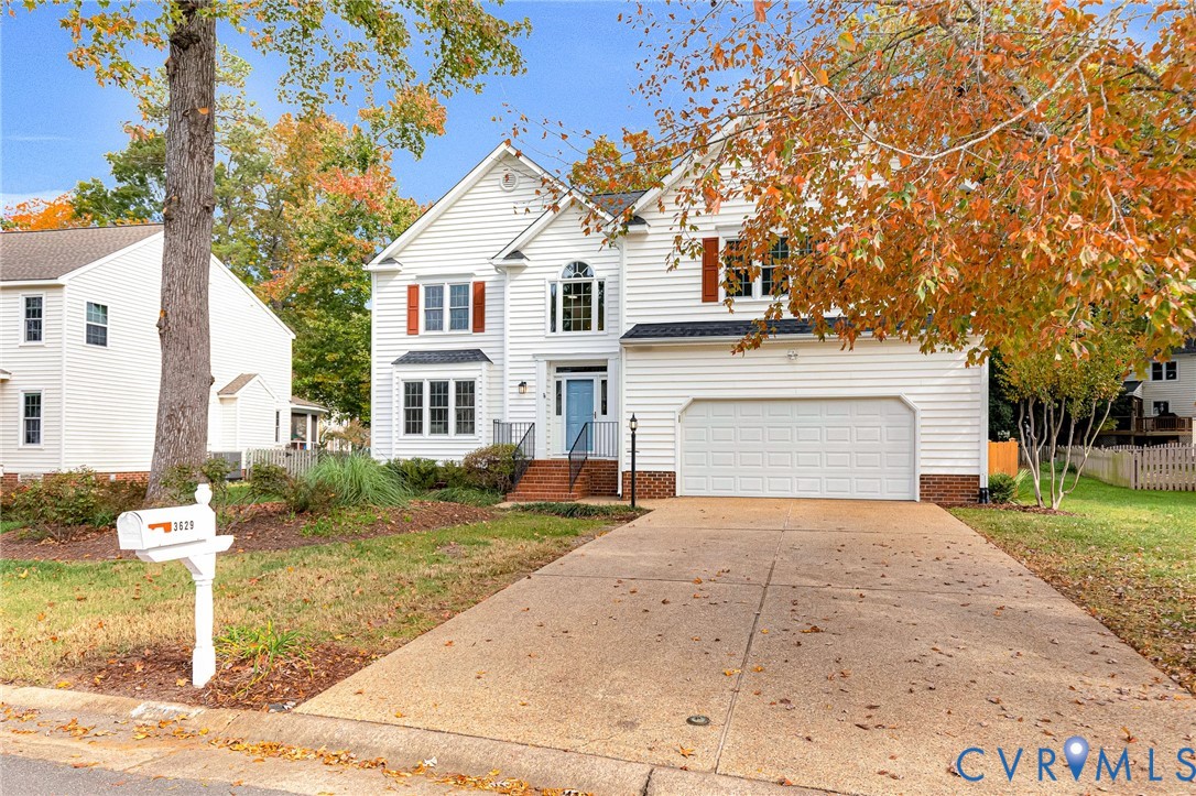 Two-story residence featuring white horizontal siding, contrasting shutters, arched window accents, a front-facing attached garage, and a concrete driveway Two-story residence featuring white horizontal siding, contrasting shutters, arched window accents, a front-facing attached garage, and a concrete driveway