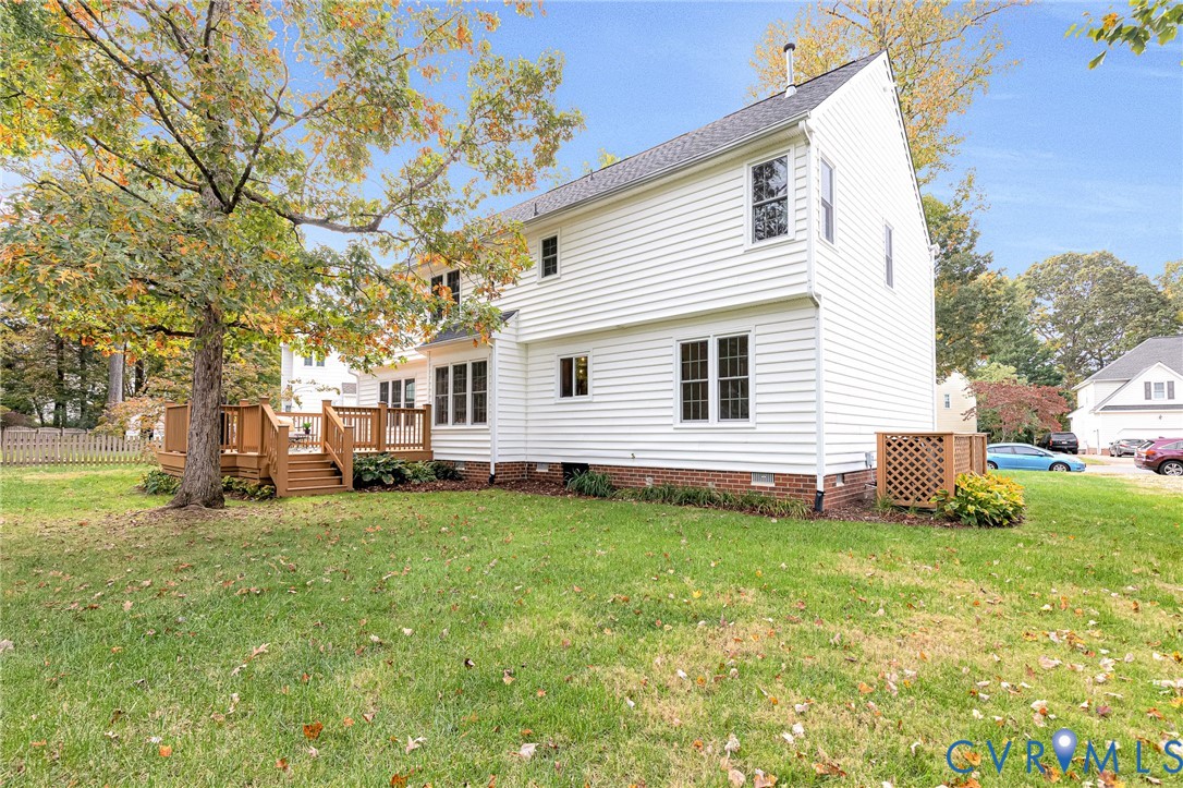 Two-story residence featuring white horizontal siding, a brick foundation, a raised wood deck with balustrades, and multi-pane windows