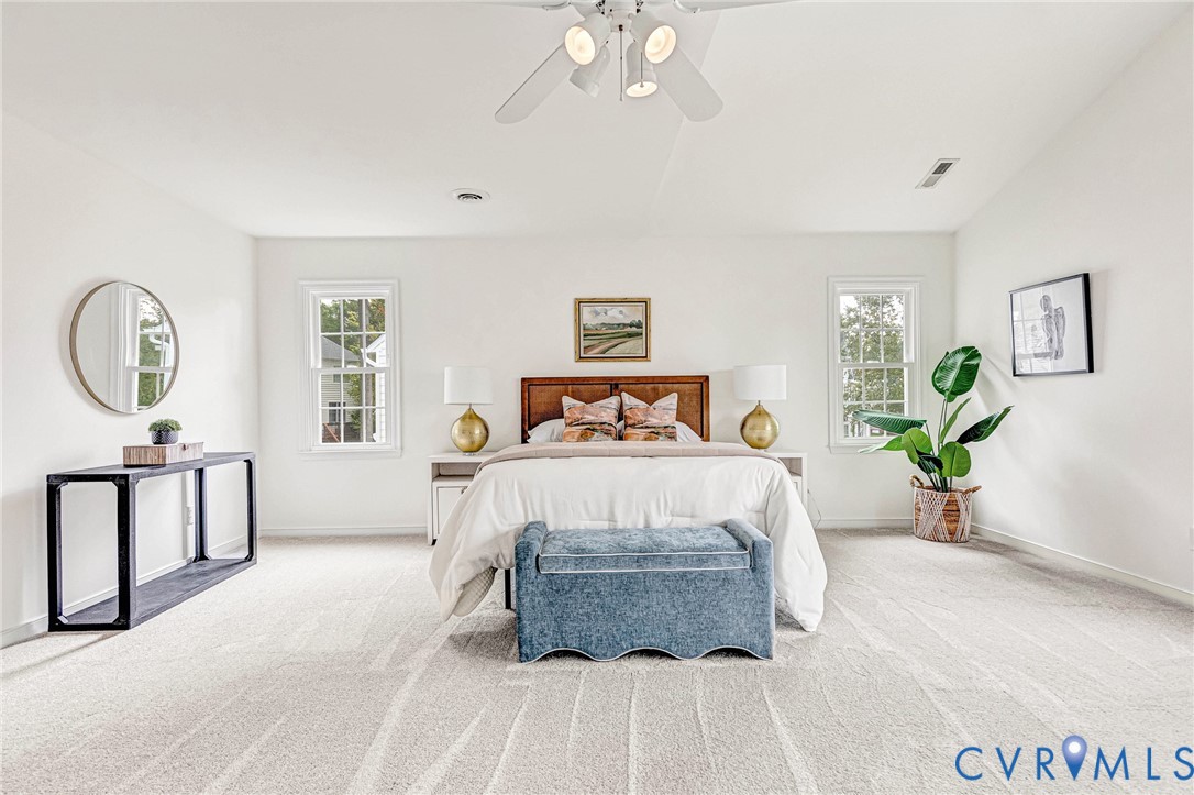 Neutral-toned wall-to-wall carpeting, vaulted ceilings, dual-pane windows with grid mullions, and an integrated ceiling fan with multi-directional lighting