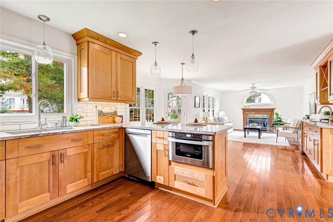 Kitchen featuring natural wood cabinetry, stone-finish countertops, stainless steel appliances, pendant lighting, and wood-finish flooring
