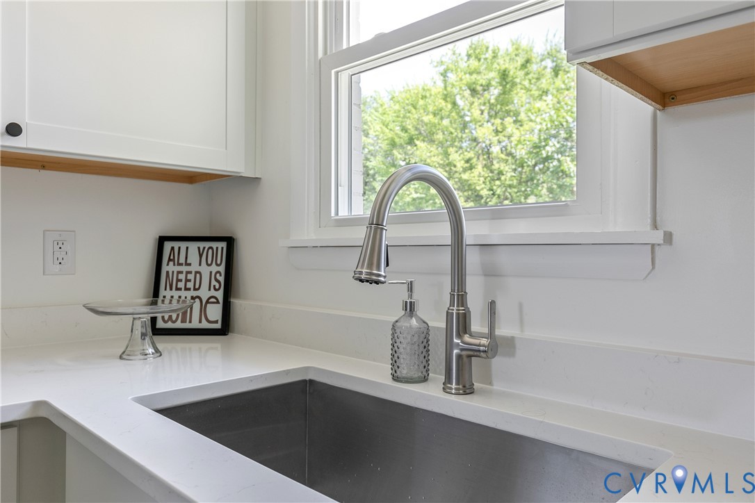 Stainless steel undermount kitchen sink featuring a brushed nickel high-arc pull-down faucet, quartz countertop, and white shaker-style cabinetry