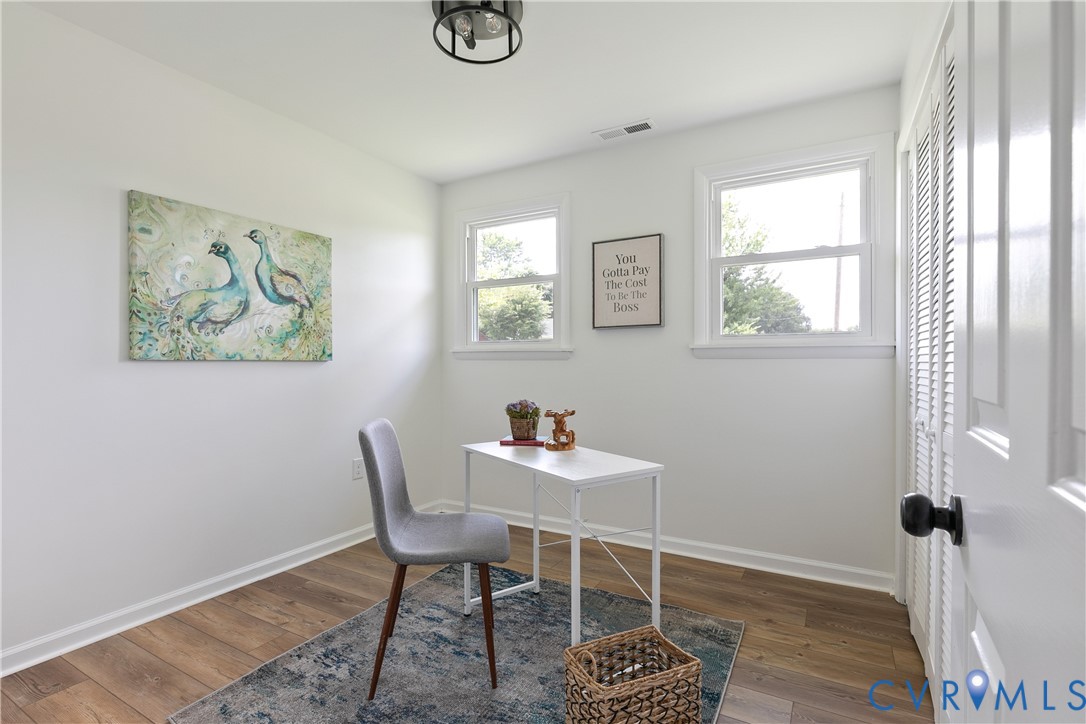 Room featuring wood-finish flooring, two double-hung windows, and white bifold closet doors with matte black hardware