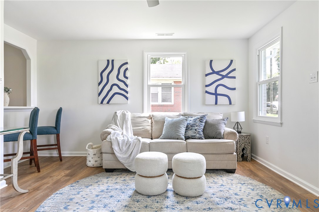 Living space featuring wood-finish flooring, crisp neutral wall paint, and multiple double-hung windows providing natural light