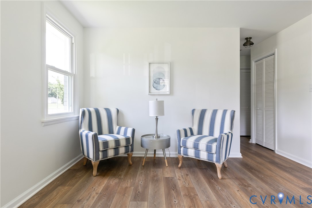 Bright room featuring wood-finish flooring, a double-hung window, and a louvered closet door