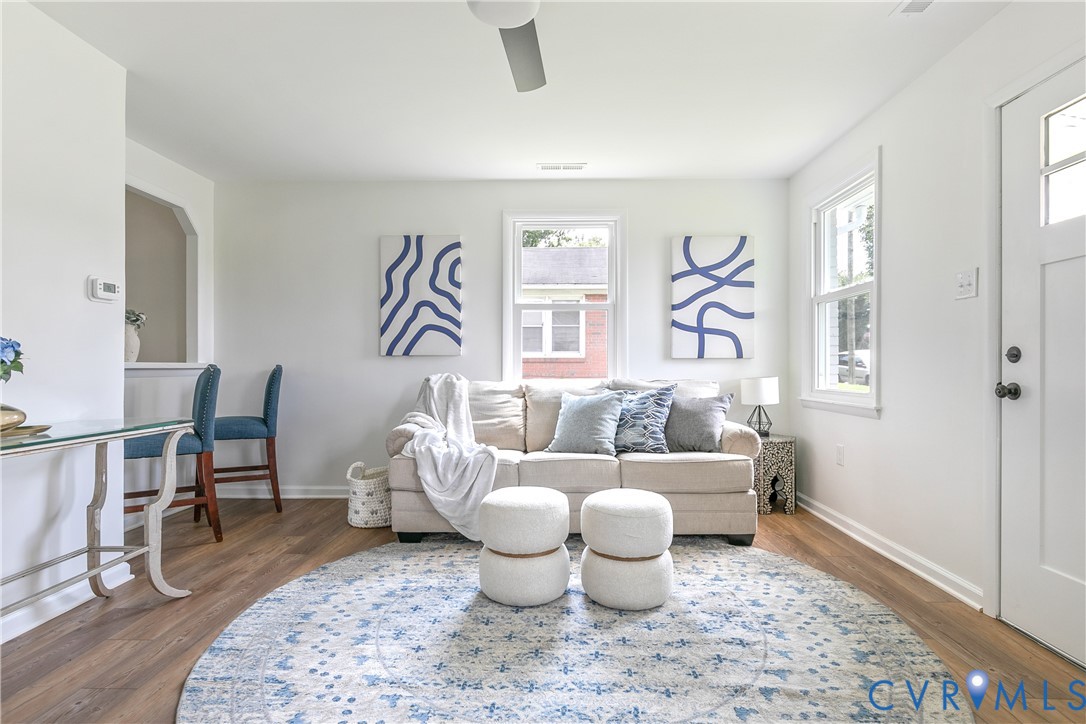 Open-concept interior featuring wood-finish flooring, crisp white wall finishes, a pass-through wall opening, and a multi-pane entry door