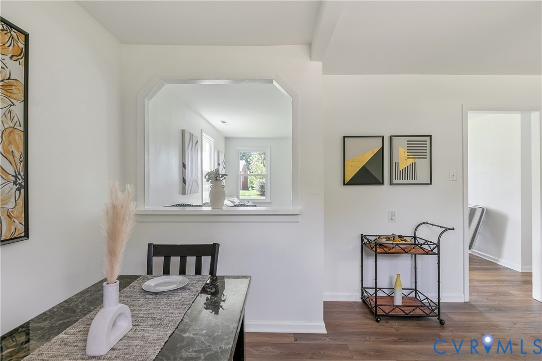 Interior space featuring wood-finish flooring, a pass-through window with millwork trim, and neutral wall tones