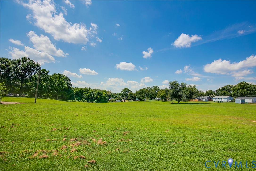 Expansive parcel of land featuring level topography, open grassy terrain, and clusters of mature trees
