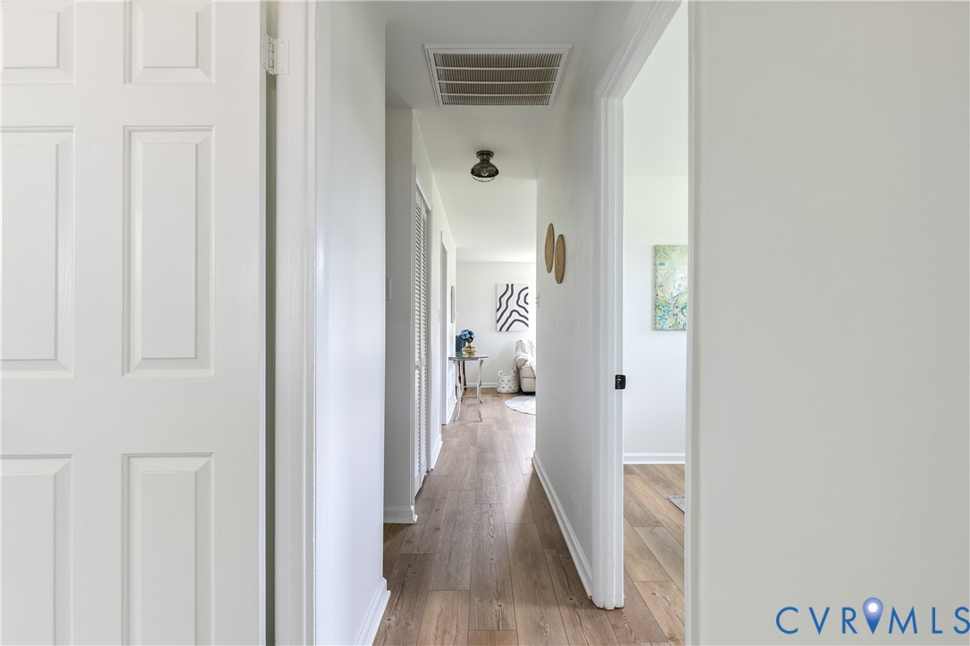 Interior hallway featuring wood-finish flooring, six-panel interior doors, and a ceiling-mounted light fixture