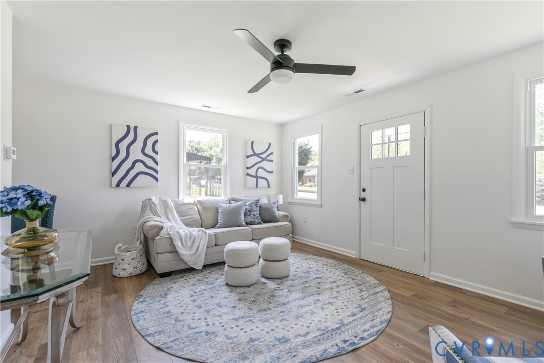 Wood-finish flooring, multi-pane exterior door with glass detailing, three-blade ceiling fan with integrated light, and crisp white wall finishes