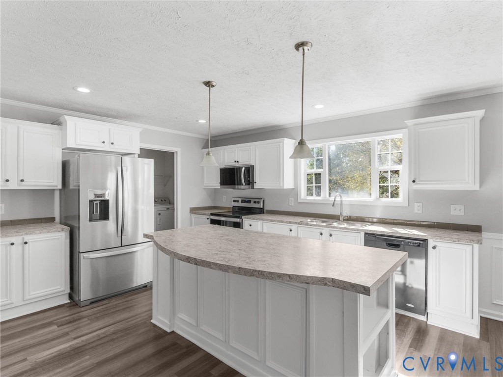 Kitchen featuring white cabinetry, stone-finish countertops, stainless steel appliances, a central island, and wood-finish flooring Kitchen featuring white cabinetry, stone-finish countertops, stainless steel appliances, a central island, and wood-finish flooring