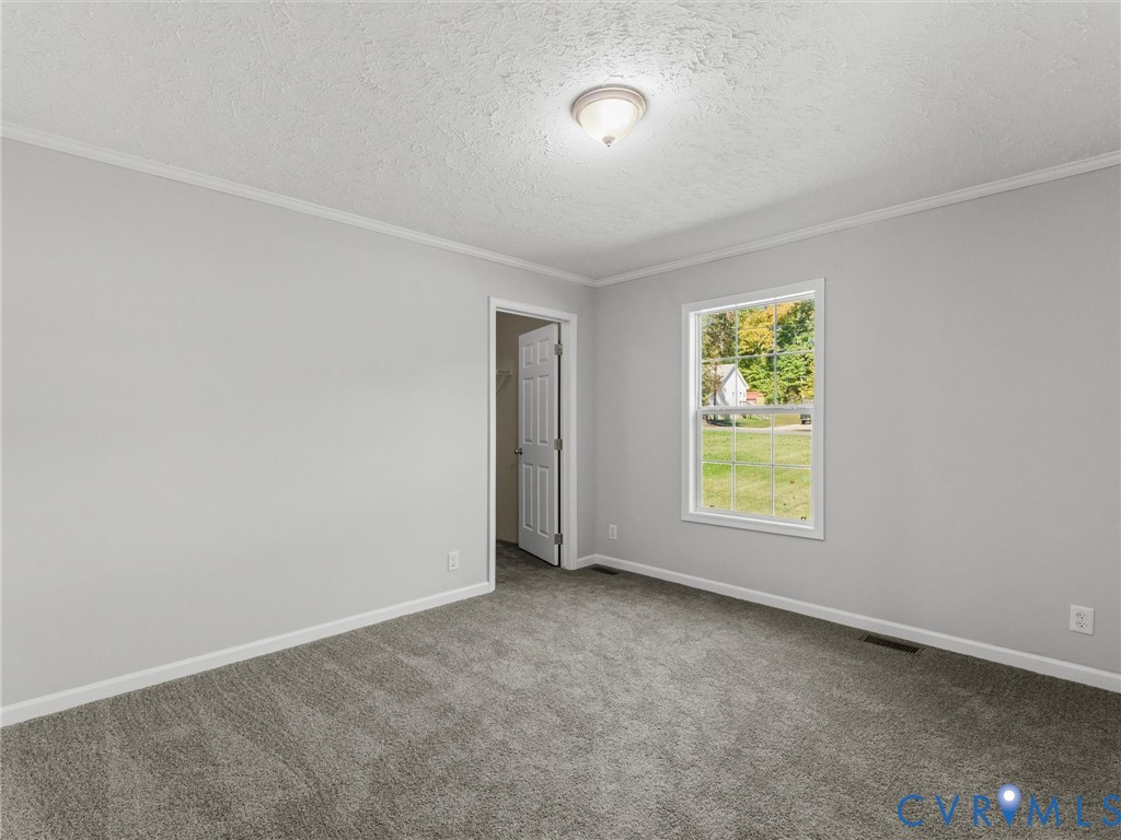 Neutral-toned walls, wall-to-wall carpeting, window with pane detailing, and a flush-mount ceiling light fixture