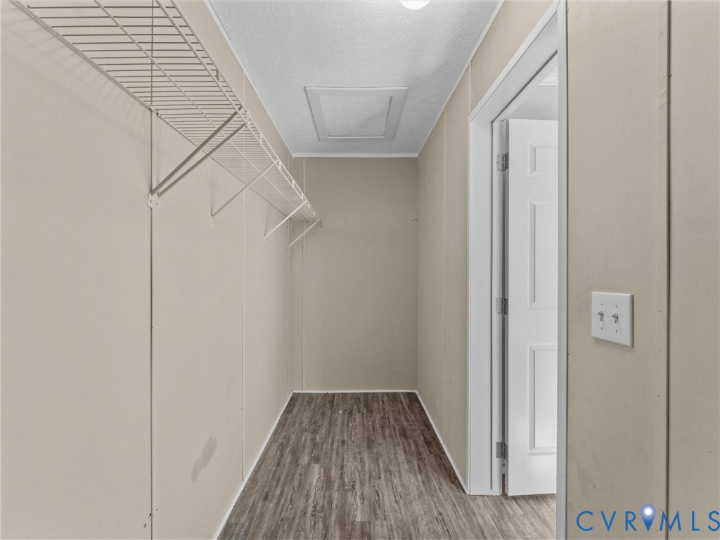 Walk-in closet featuring wood-finish flooring, white paneled door, and wall-mounted wire shelving