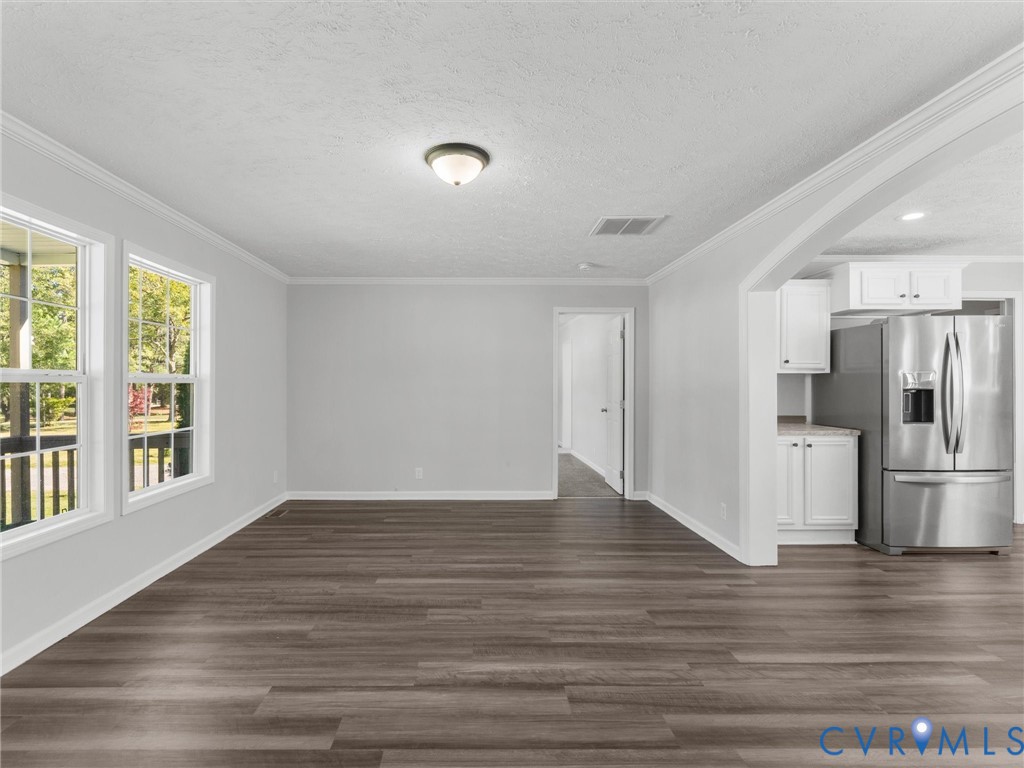 Interior space featuring wood-finish flooring, white cabinetry, stainless steel refrigerator, and crown molding Interior space featuring wood-finish flooring, white cabinetry, stainless steel refrigerator, and crown molding