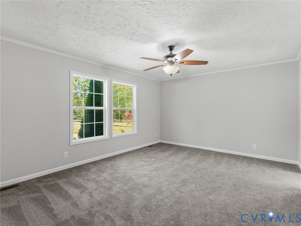 Neutral interior featuring plush wall-to-wall carpeting, multiple windows with grid muntins, and a ceiling fan with integrated light fixture