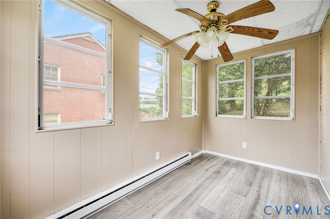 Interior space featuring wood-finish flooring, multiple windows, and a ceiling fan with light fixture Interior space featuring wood-finish flooring, multiple windows, and a ceiling fan with light fixture