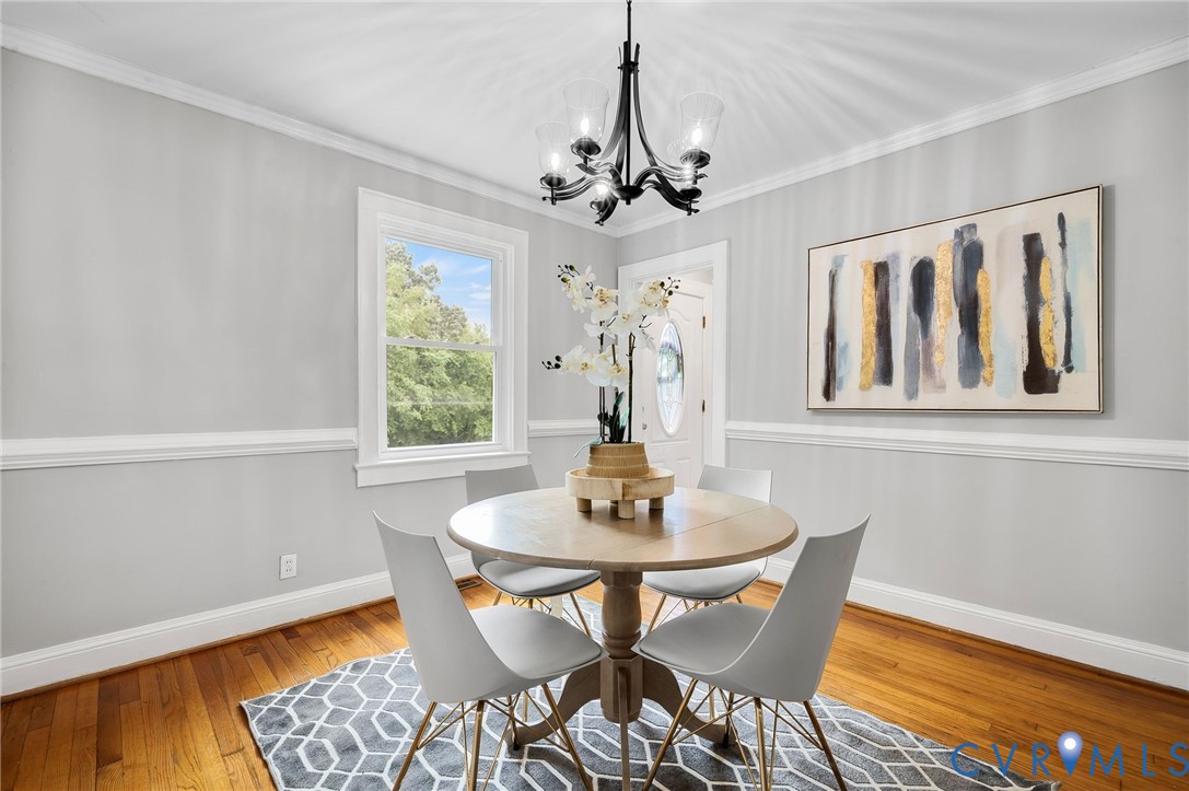 Dining area featuring hardwood flooring, crown molding, chair rail detailing, and a multi-arm iron chandelier Dining area featuring hardwood flooring, crown molding, chair rail detailing, and a multi-arm iron chandelier