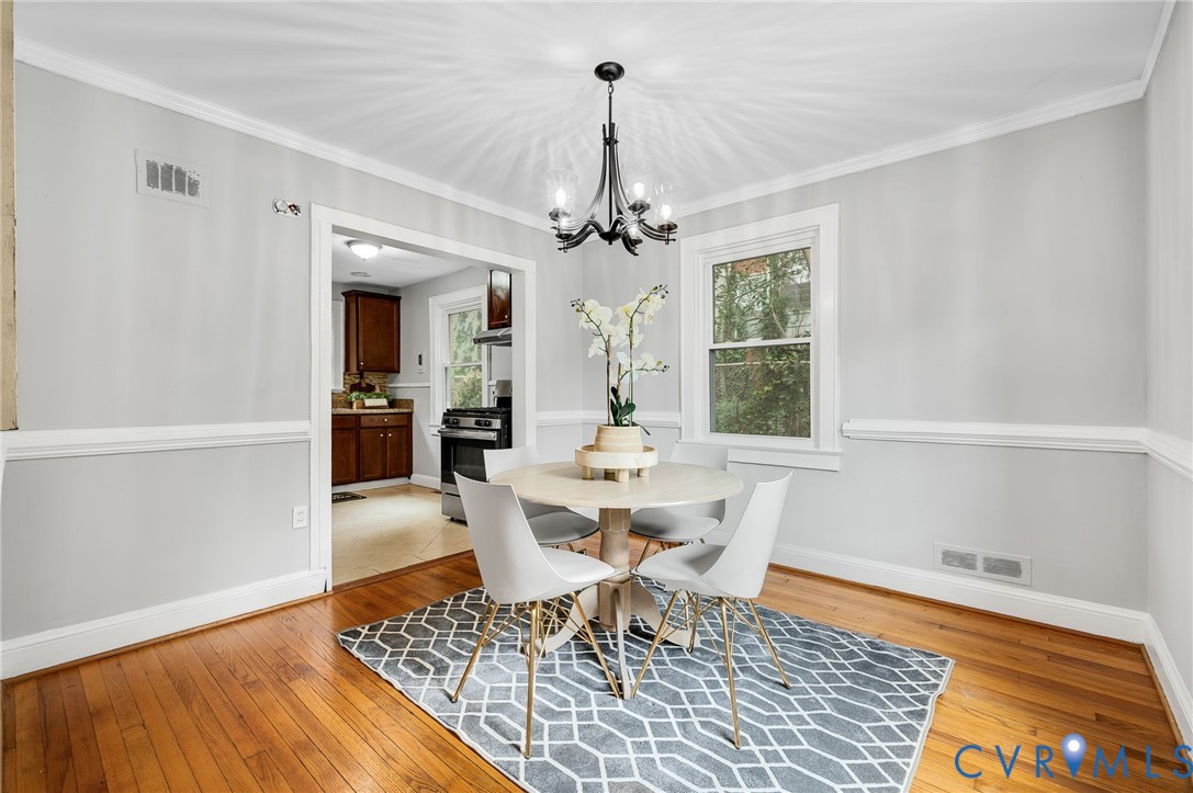 Dining area featuring wood-finish flooring, chair rail molding, and a multi-arm metal chandelier Dining area featuring wood-finish flooring, chair rail molding, and a multi-arm metal chandelier