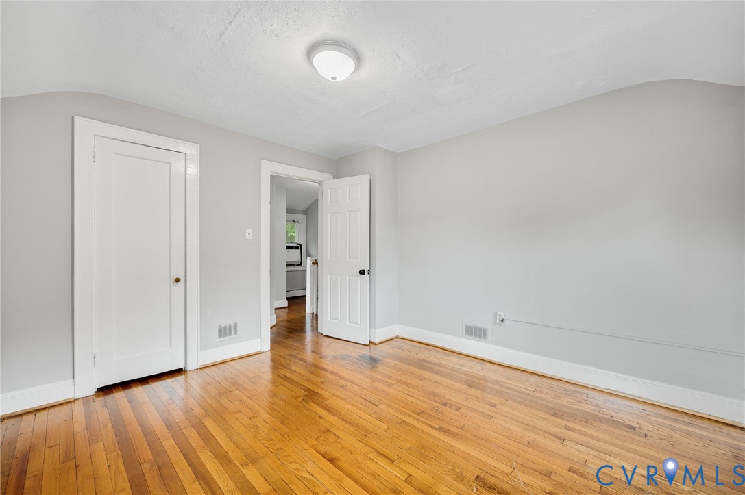 Room featuring wood-finish flooring, neutral wall paint, a ceiling-mounted flush light fixture, and two interior doors with paneled detailing
