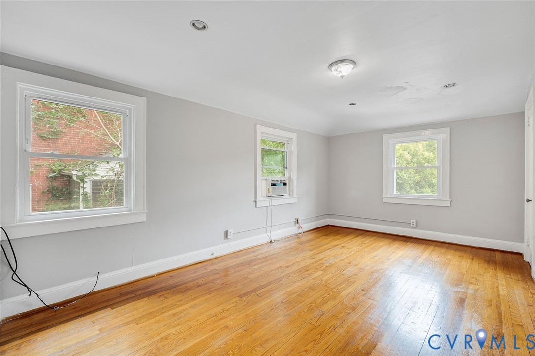 Interior room featuring wood-finish flooring, recessed lighting, and three double-hung windows with white casing