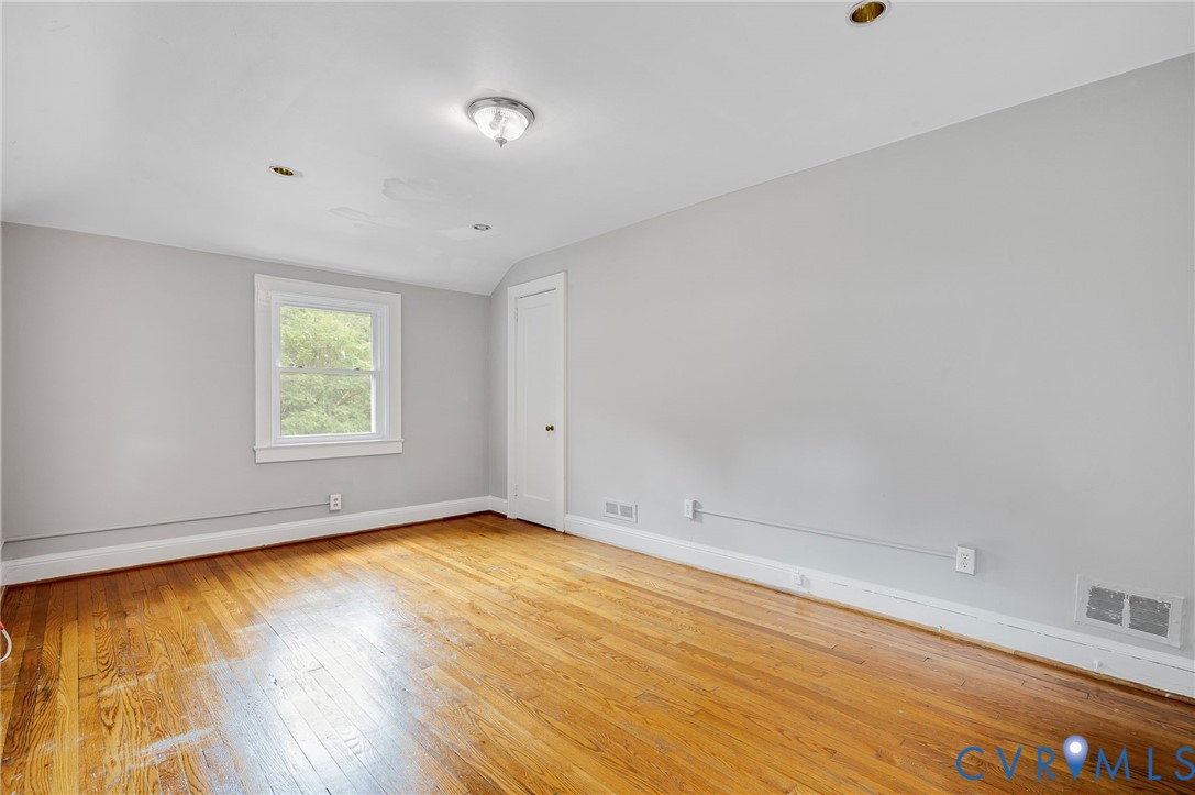 Room featuring wood-finish flooring, neutral wall paint, a single window, and a flush-mount ceiling fixture with recessed lighting