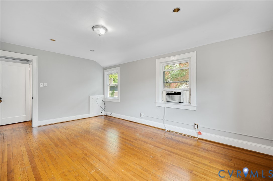 Interior room featuring wood-finish flooring, neutral wall paint, two double-hung windows, and ceiling-mounted light fixtures