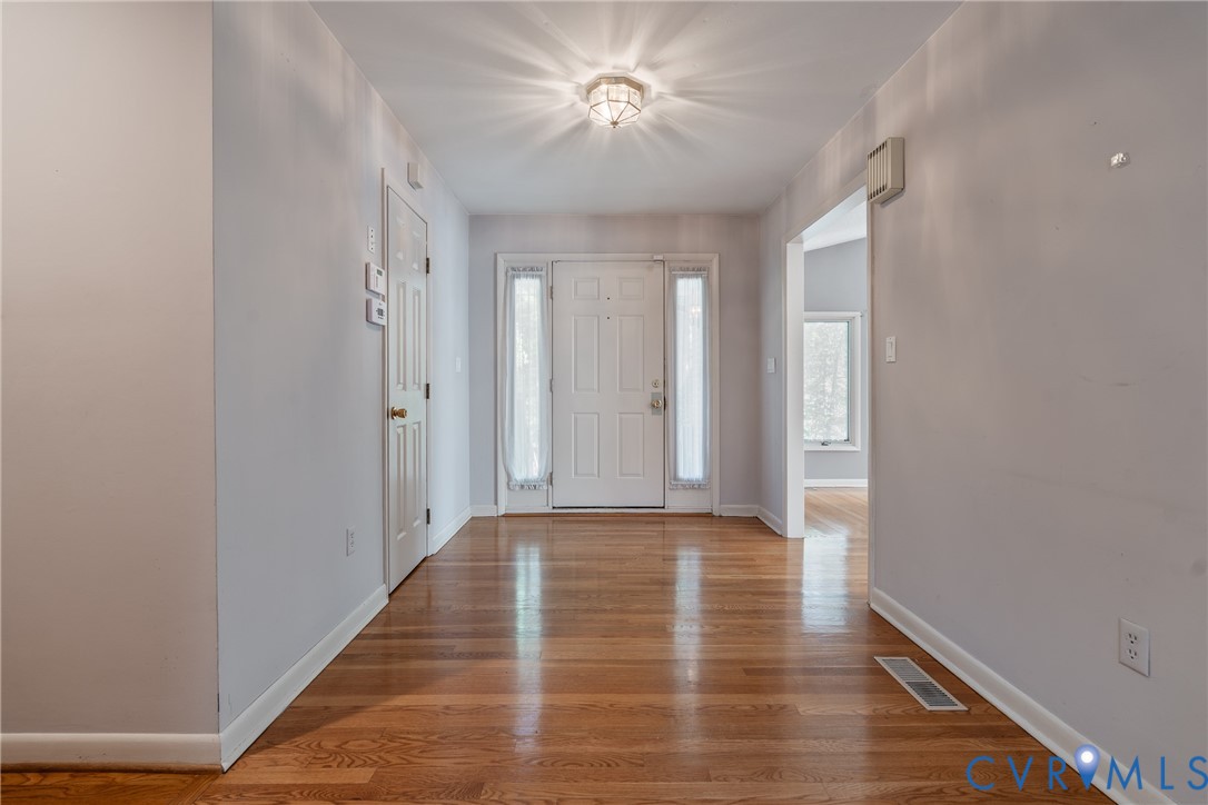 Entryway featuring wood-finish flooring, a paneled front door with sidelights, and a flush-mount ceiling light fixture