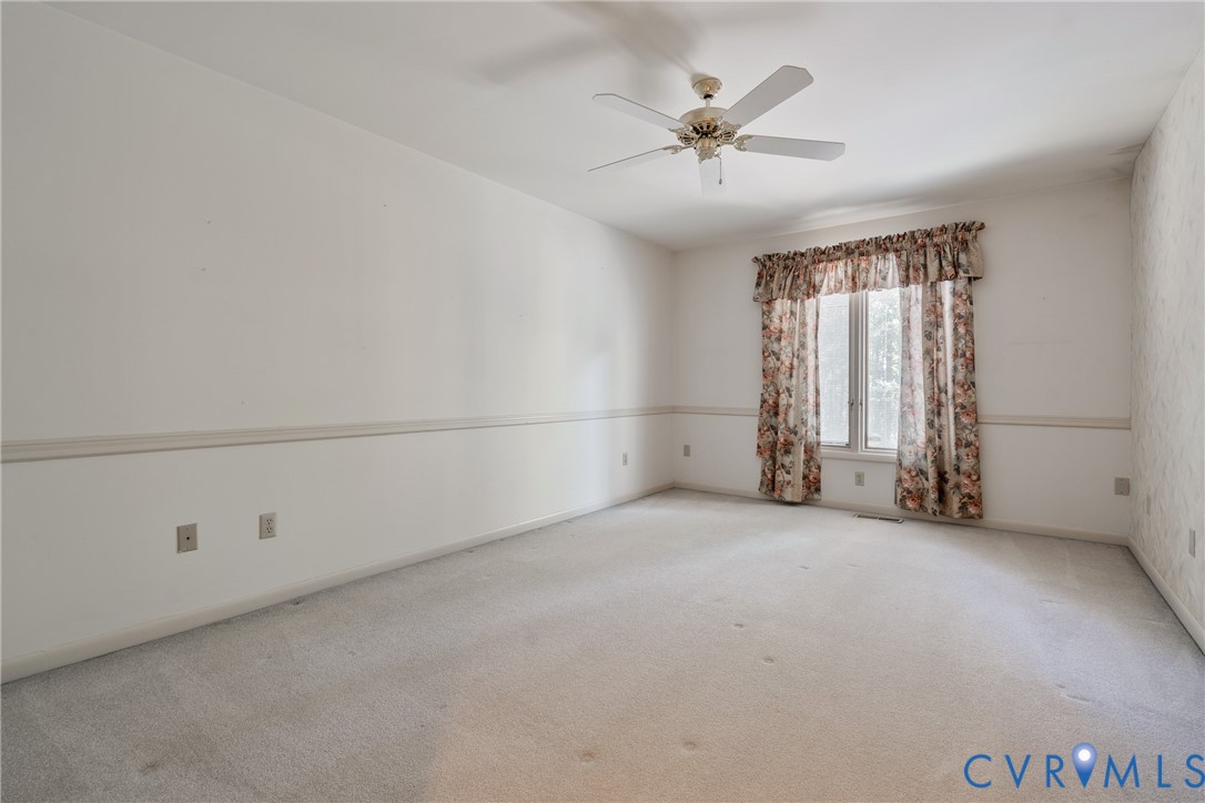 Interior space featuring carpeting, chair rail molding, and a ceiling fan