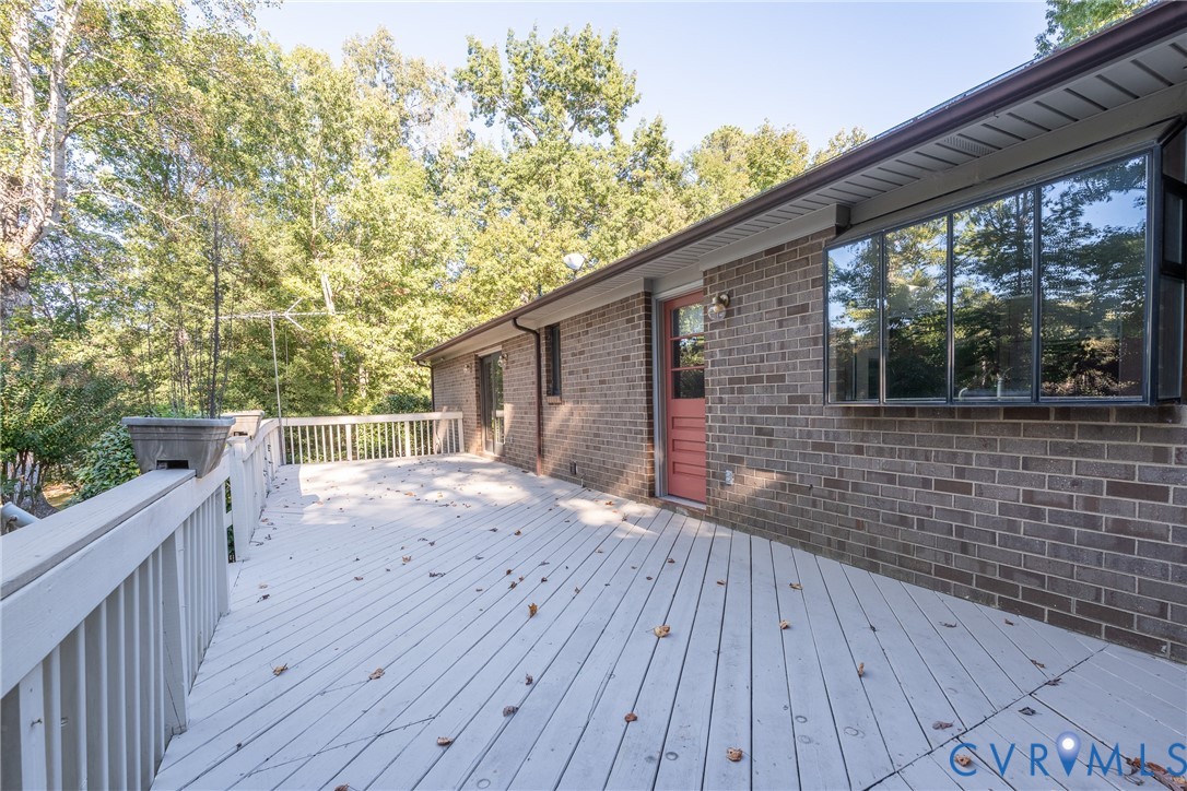 Exterior deck with painted wood railing, brick masonry siding, bay window, and exterior door with glass insert