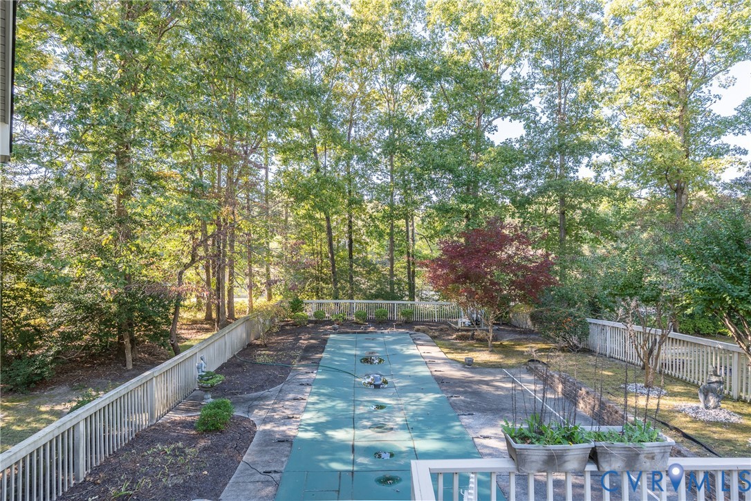 Outdoor space featuring a fenced backyard, an in-ground pool with a safety cover, and perimeter landscaping with mature trees
