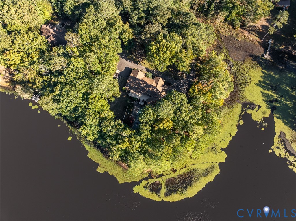 Waterfront property featuring extensive perimeter shoreline, mature woodland canopy, private paved driveway, and detached structure