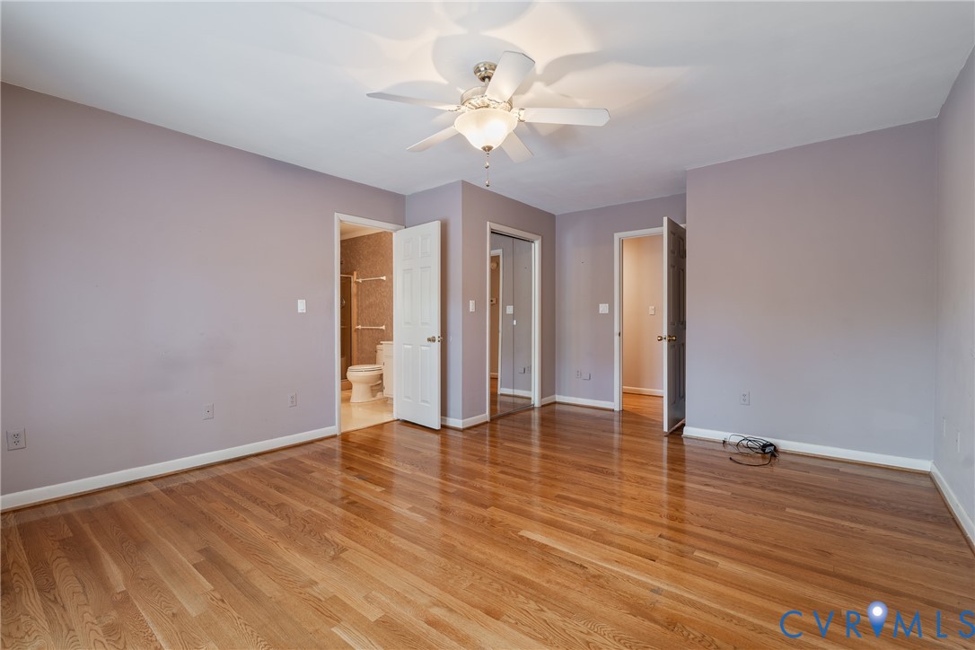 Room featuring wood-finish flooring, a ceiling fan with integrated lighting, and mirrored sliding closet doors