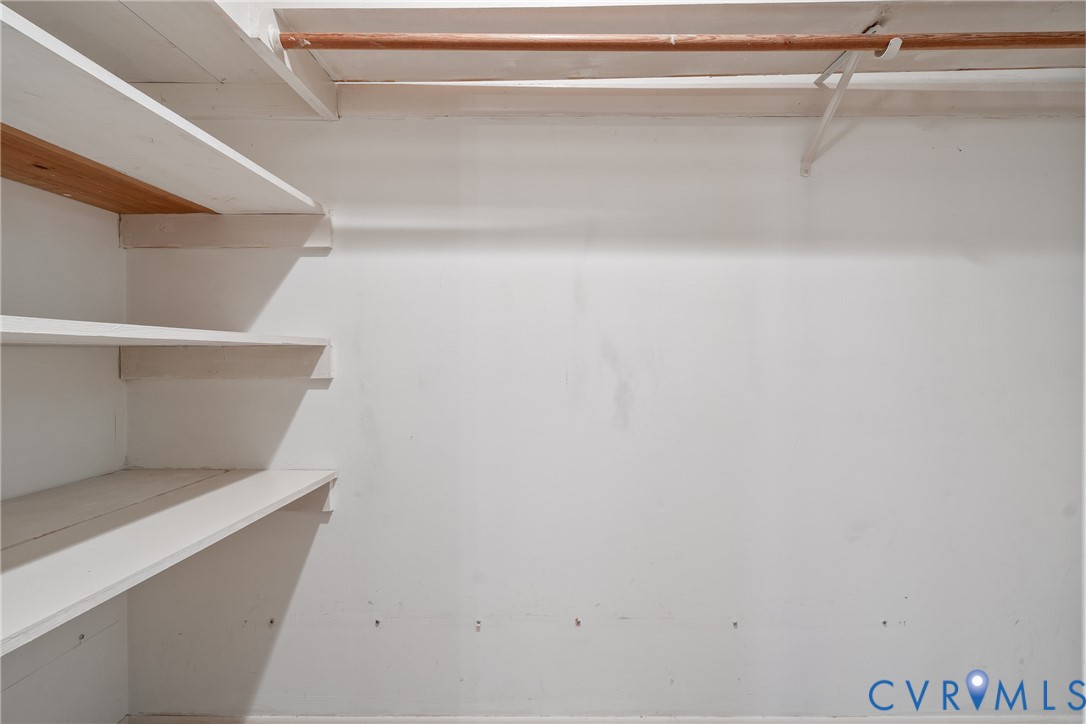 Storage area featuring white painted wooden shelving and a horizontal hanging rod
