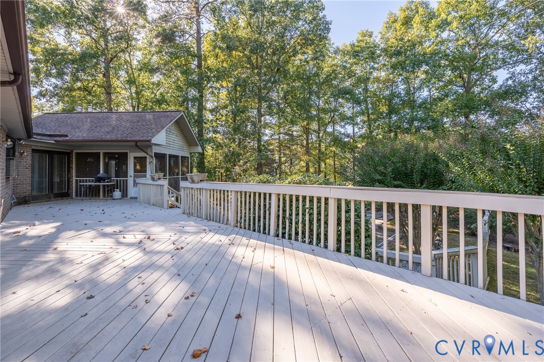 Expansive multi-level wood deck featuring painted railings and a covered screened-in porch with brick exterior detailing