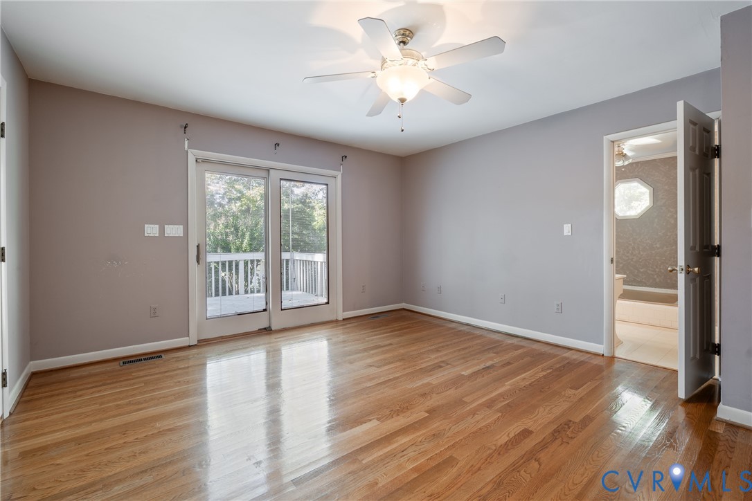 Interior room featuring wood-finish flooring, a ceiling fan with integrated lighting, and glass sliding doors leading to an outdoor deck