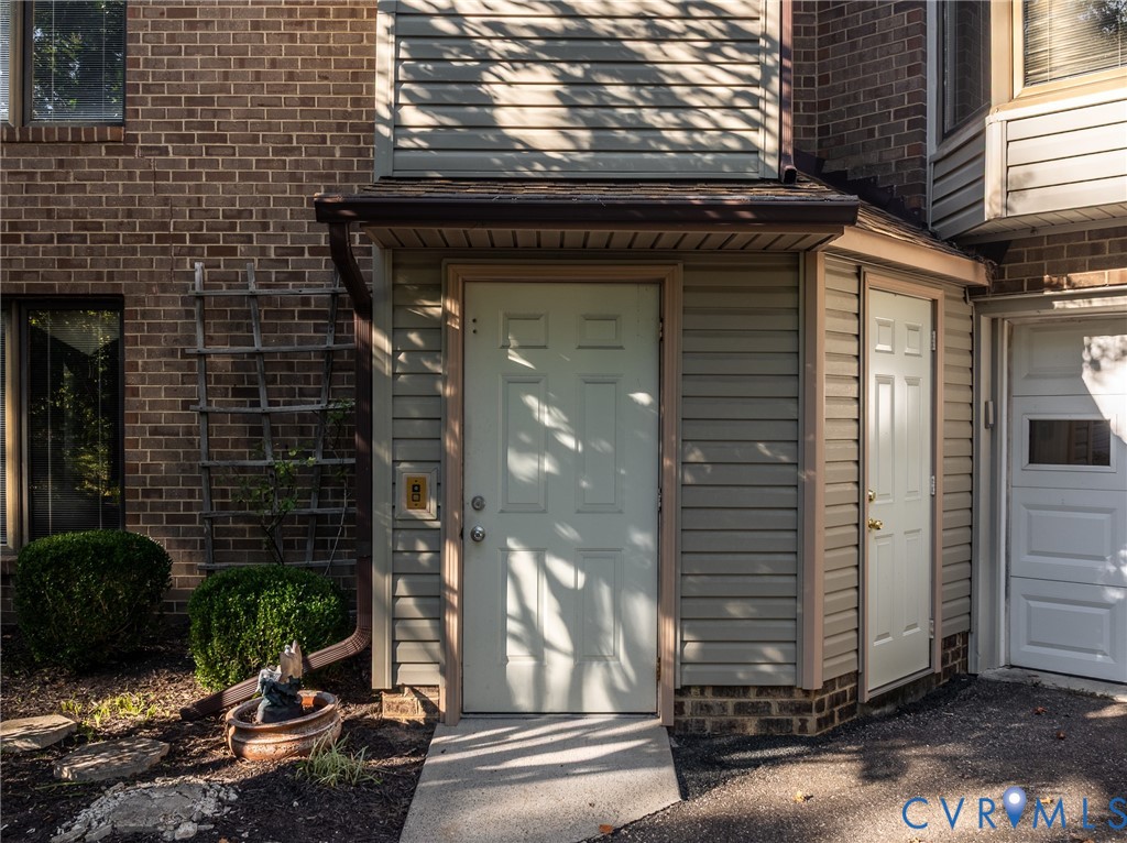 Multi-textured exterior featuring brick masonry and horizontal siding, covered entryway, and attached garage