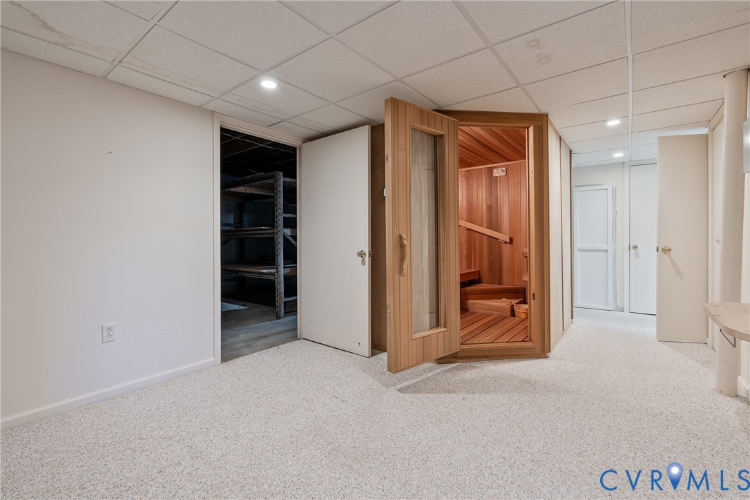 Custom-built cedar sauna with a glass-paneled door, recessed lighting, and wall-to-wall carpeting