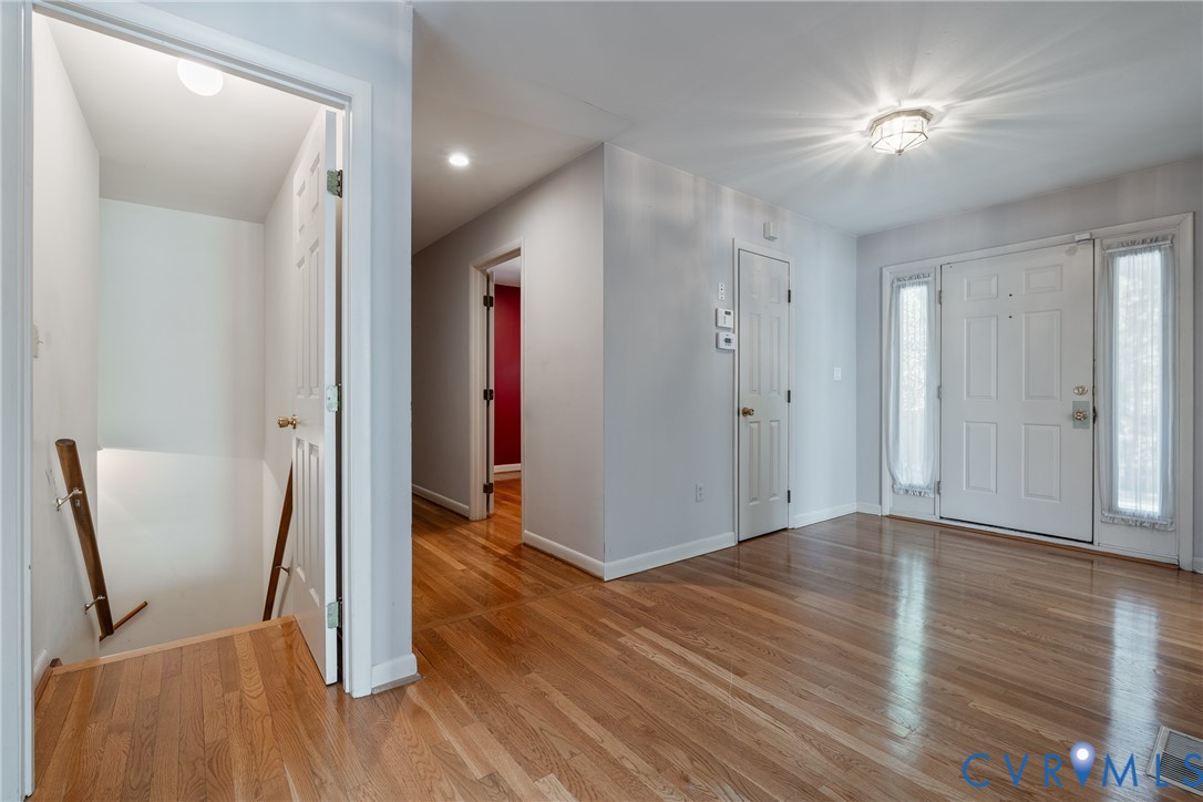 Entryway featuring wood-finish flooring, a paneled front door with flanking sidelights, flush-mount ceiling lighting, and a staircase with a wood handrail