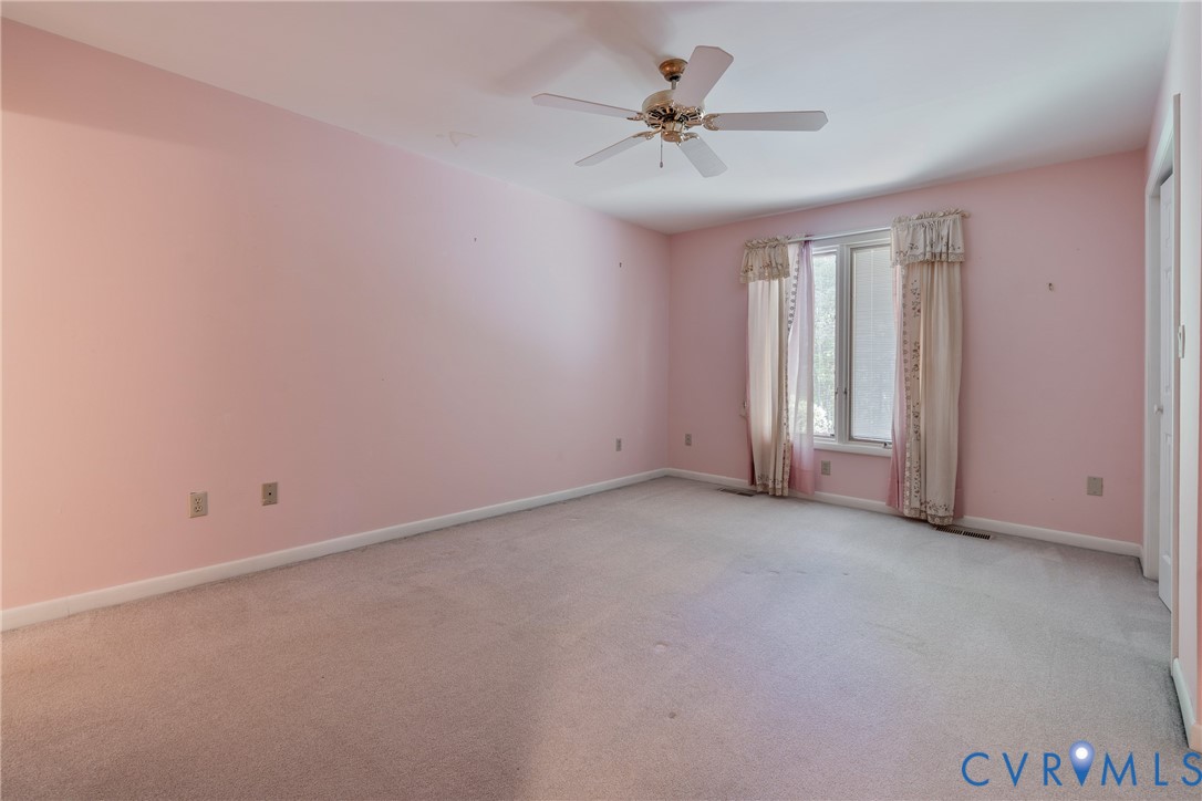 Interior room featuring wall-to-wall carpeting, a ceiling fan with integrated lighting, and a multi-panel window