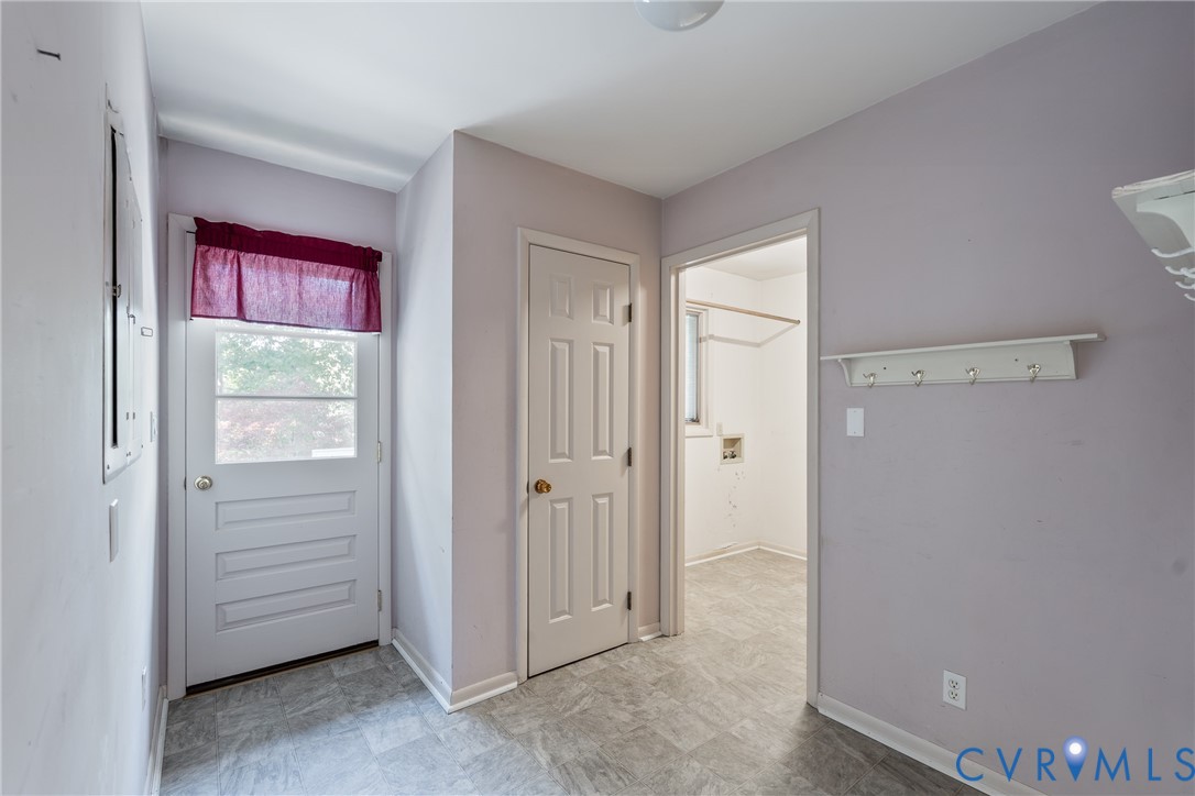 Utility room featuring resilient stone-finish flooring, a solid-panel door, and a built-in wall-mounted coat rack