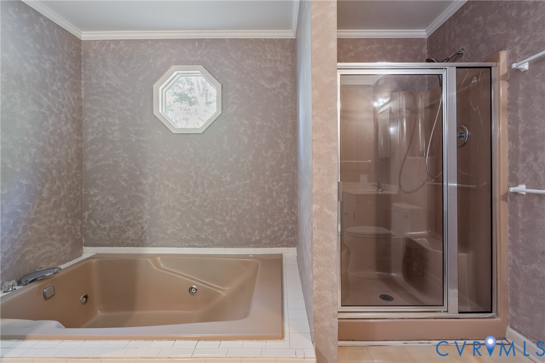 Built-in jetted soaking tub with tile surround, standalone shower with glass enclosure, and octagonal window