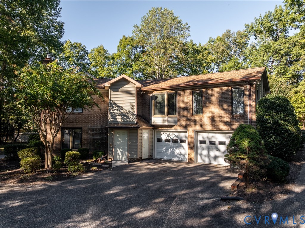 Two-story brick exterior featuring a multi-car garage, asphalt driveway, bay window, and gabled roofline