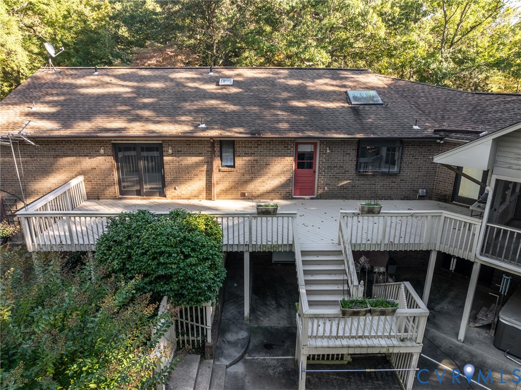 Multi-level wooden deck featuring stairs and railing, brick exterior, skylights, and glass-paned entry door