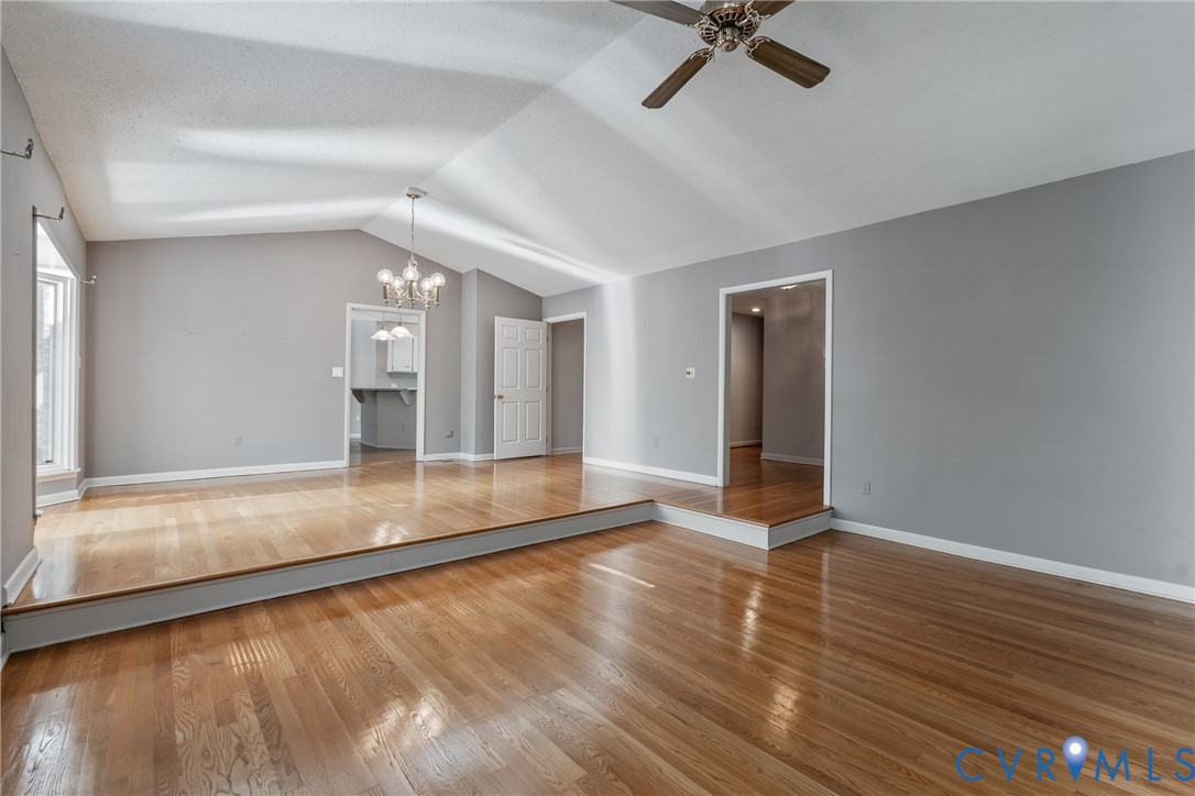 Vaulted ceilings featuring a multi-arm chandelier, wood-finish flooring, and a multi-level floor plan