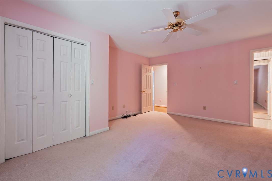Room featuring carpeted flooring, a four-panel bi-fold closet, and a ceiling-mounted fan with integrated light fixture