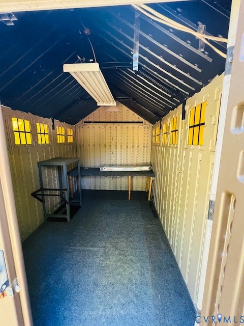 Outbuilding featuring a vaulted ceiling, multiple fixed windows, integrated overhead lighting, and reinforced structural walls