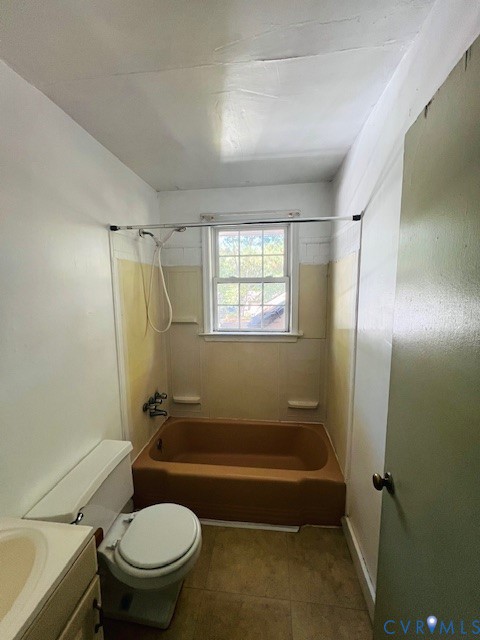 Bathroom featuring a single-basin vanity, a standard porcelain toilet, and a bathtub with a shower head and integrated surround