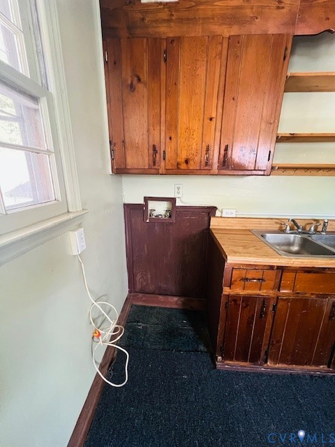 Custom wood cabinetry, dual-basin stainless steel sink, solid wood-surface countertop, and open wall shelving