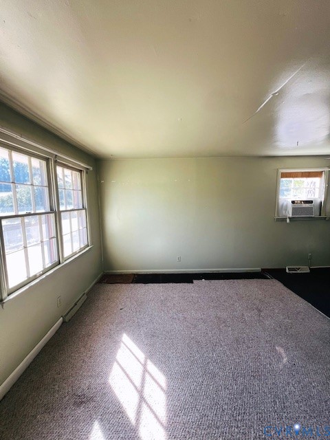 Room featuring multi-pane windows, wall-to-wall carpeting, and a wall-mounted air conditioning unit
